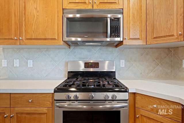 11871 W Wilmont St, Boise, ID 83709 - kitchen with appliances with stainless steel finishes, light countertops, decorative backsplash, and brown cabinetry