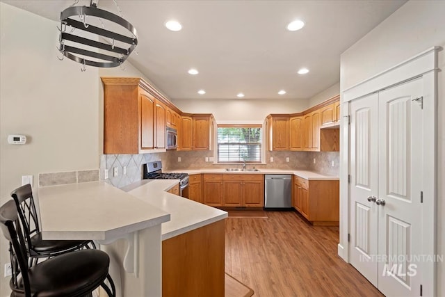 11871 W Wilmont St, Boise, ID 83709 - kitchen featuring stainless steel appliances, a peninsula, light wood-type flooring, a sink, and light countertops