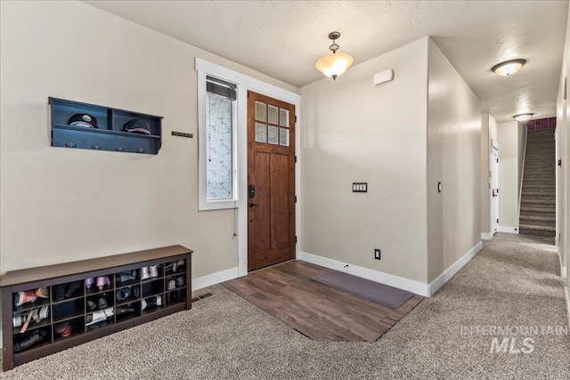 carpeted foyer entrance with a textured ceiling