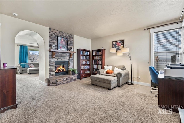 carpeted office with a textured ceiling and a stone fireplace