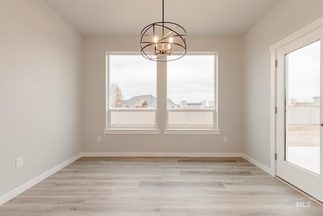 unfurnished dining area with light hardwood / wood-style floors and a notable chandelier