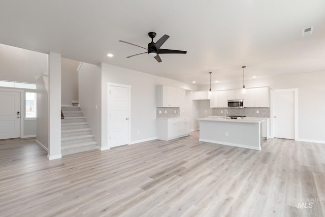 unfurnished living room featuring ceiling fan and light hardwood / wood-style flooring