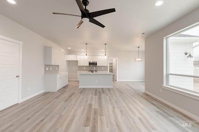 unfurnished living room featuring ceiling fan and light hardwood / wood-style floors