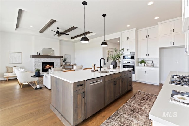 kitchen featuring a sink, a tray ceiling, appliances with stainless steel finishes, and white cabinetry