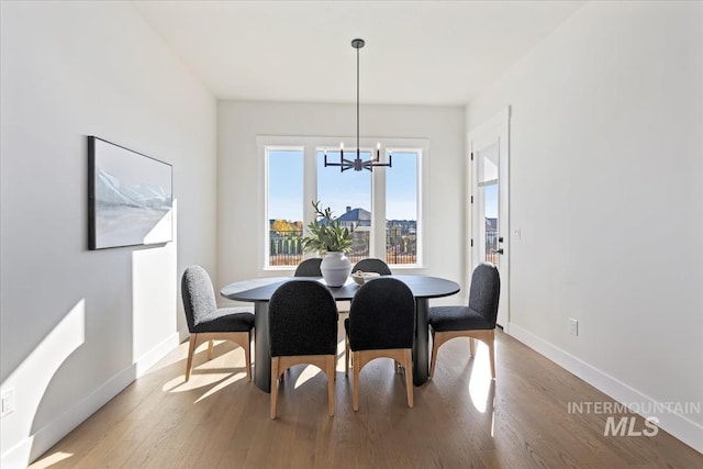 dining space with wood finished floors, baseboards, and a chandelier