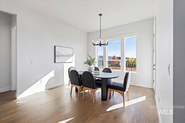 dining space featuring baseboards, an inviting chandelier, and wood finished floors