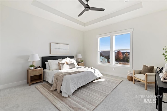 bedroom featuring a tray ceiling, baseboards, and carpet