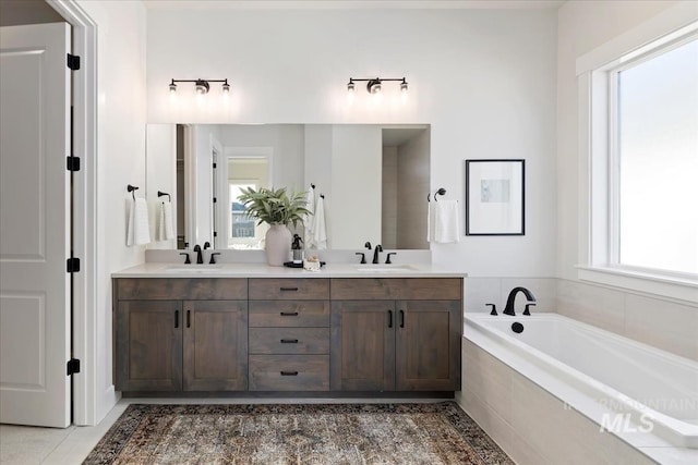 full bath with a bath, double vanity, and a sink