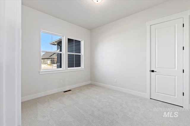 carpeted spare room featuring visible vents and baseboards