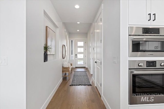 corridor with recessed lighting, baseboards, and wood finished floors