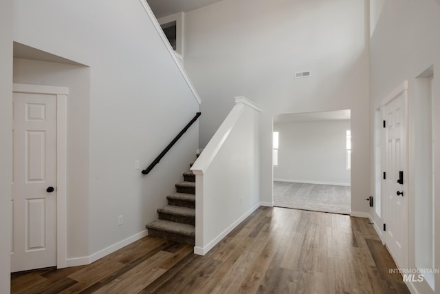 entryway with a high ceiling, wood finished floors, visible vents, and baseboards