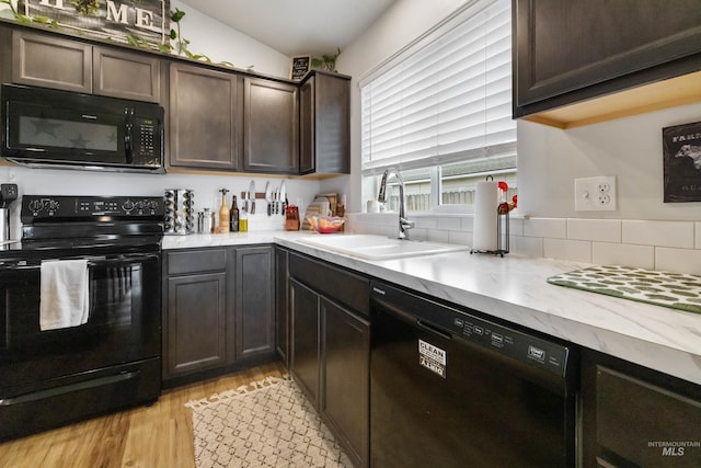 kitchen featuring black appliances, light wood-style flooring, a sink, dark brown cabinetry, and light countertops