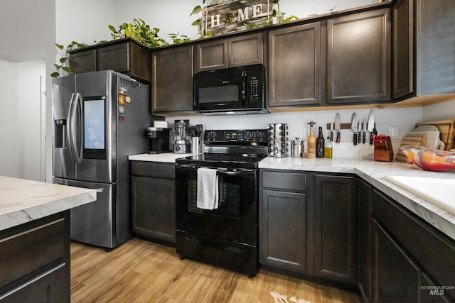 kitchen with black appliances, light wood-style flooring, a sink, light countertops, and dark brown cabinets