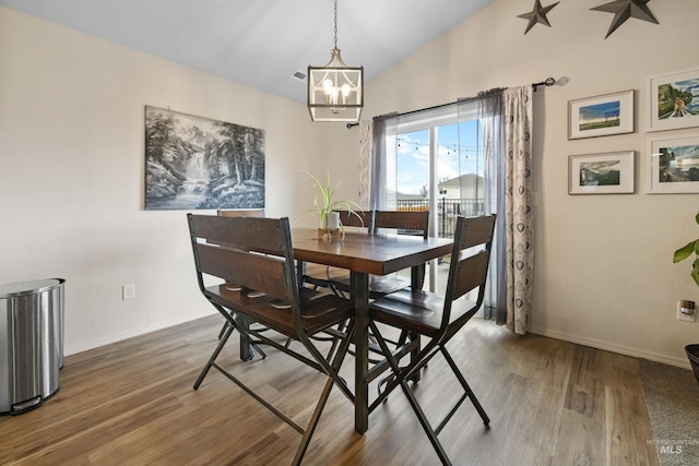 dining room with baseboards, an inviting chandelier, wood finished floors, and vaulted ceiling