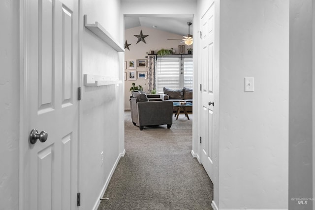 hallway featuring baseboards, carpet, and vaulted ceiling