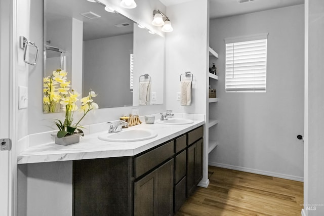 full bathroom featuring double vanity, visible vents, wood finished floors, and a sink