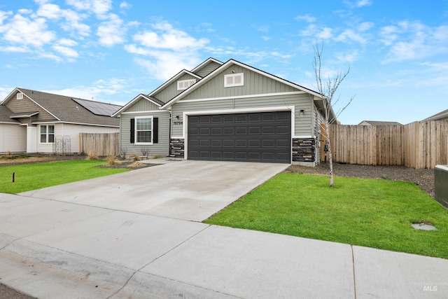 craftsman inspired home with fence, concrete driveway, a front yard, a garage, and stone siding