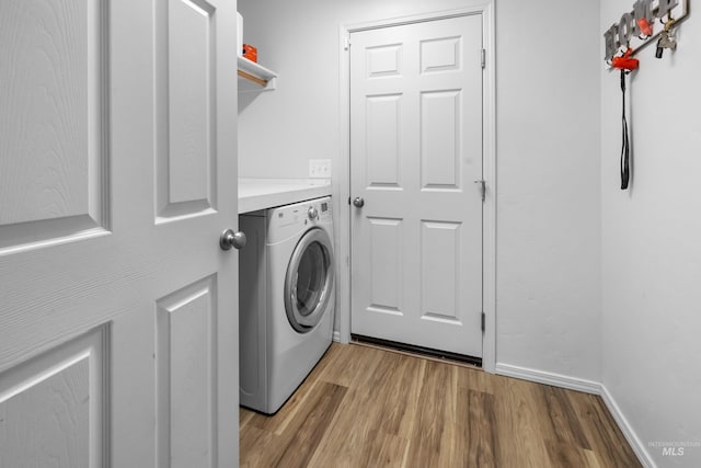 clothes washing area with laundry area, washer / dryer, light wood-type flooring, and baseboards