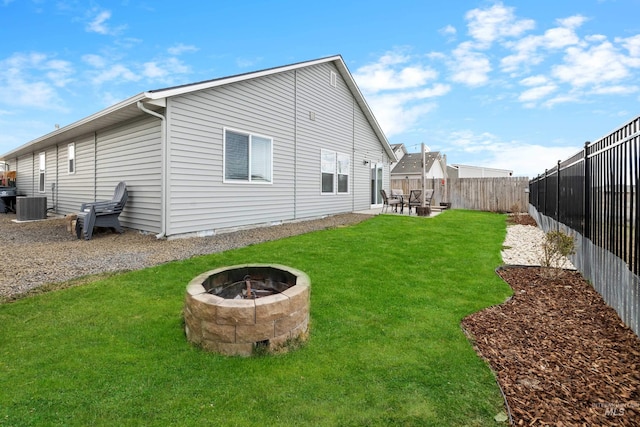 rear view of property with a patio, a lawn, a fenced backyard, and an outdoor fire pit