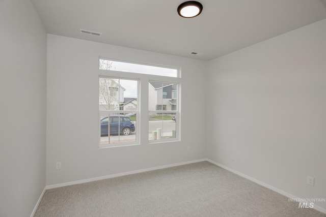 spare room featuring baseboards, visible vents, and light colored carpet