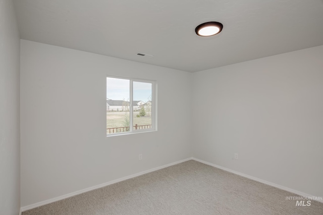 carpeted empty room featuring baseboards and visible vents