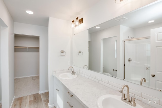 bathroom featuring a sink, a shower stall, visible vents, and wood finished floors