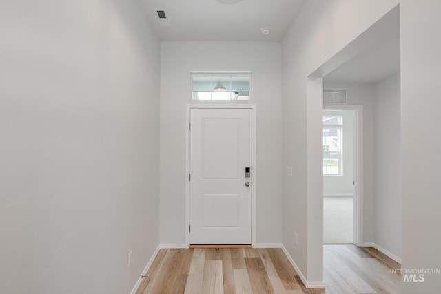 entryway with light wood-style flooring, baseboards, and plenty of natural light