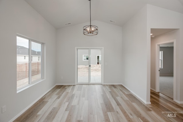 unfurnished dining area featuring an inviting chandelier, visible vents, light wood-style flooring, and lofted ceiling