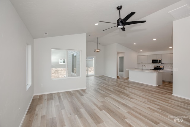 unfurnished living room featuring a sink, lofted ceiling, visible vents, recessed lighting, and light wood-style flooring