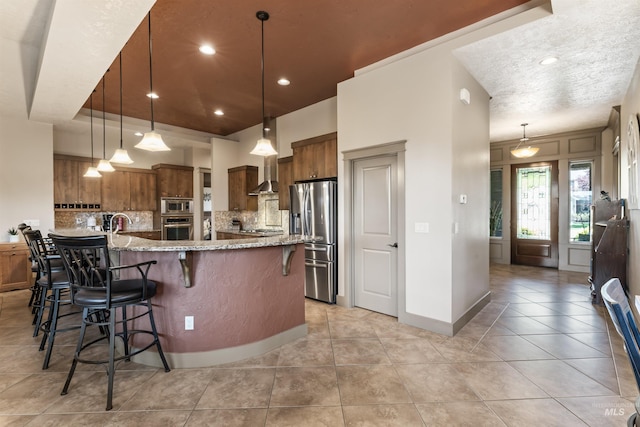 4763 S Skyridge Way, Boise, ID 83709 - kitchen with appliances with stainless steel finishes, brown cabinets, a breakfast bar area, decorative backsplash, and light stone countertops