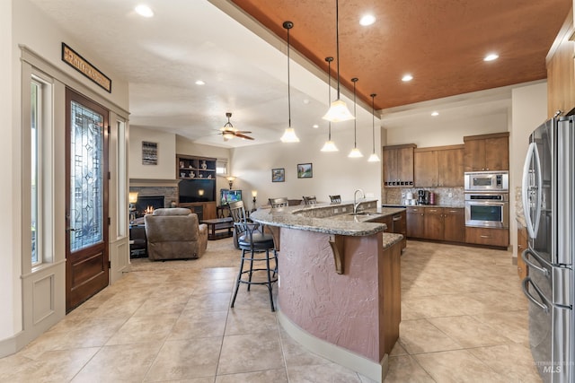 4763 S Skyridge Way, Boise, ID 83709 - kitchen featuring stainless steel appliances, open floor plan, a kitchen bar, decorative backsplash, and stone counters