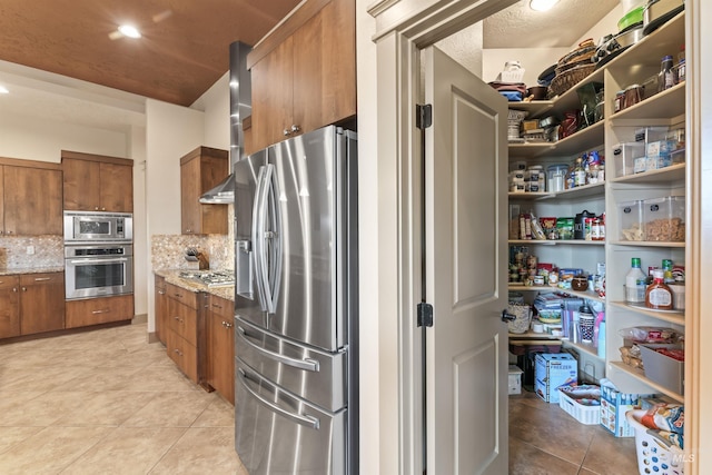 4763 S Skyridge Way, Boise, ID 83709 - kitchen featuring appliances with stainless steel finishes, brown cabinets, light tile patterned floors, and backsplash