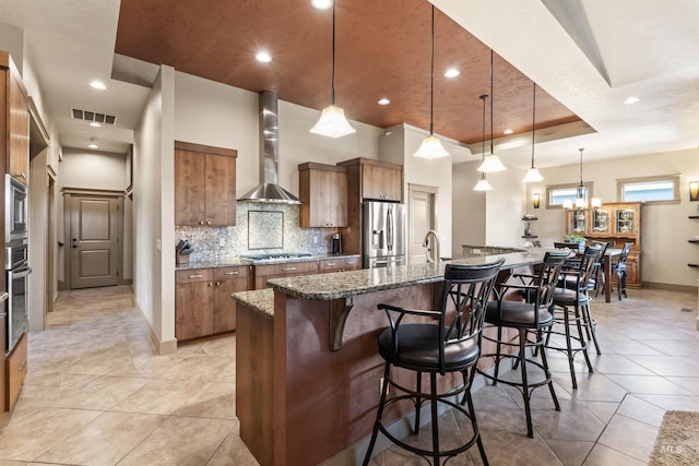 4763 S Skyridge Way, Boise, ID 83709 - kitchen with stainless steel appliances, wall chimney range hood, brown cabinets, a breakfast bar, and recessed lighting