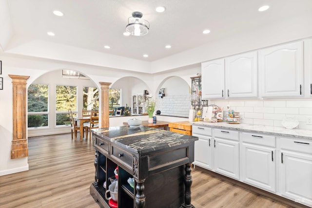 kitchen featuring a raised ceiling, ornate columns, and white cabinets