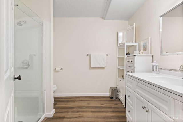 bathroom featuring vanity, a textured ceiling, hardwood / wood-style floors, toilet, and a shower with shower door