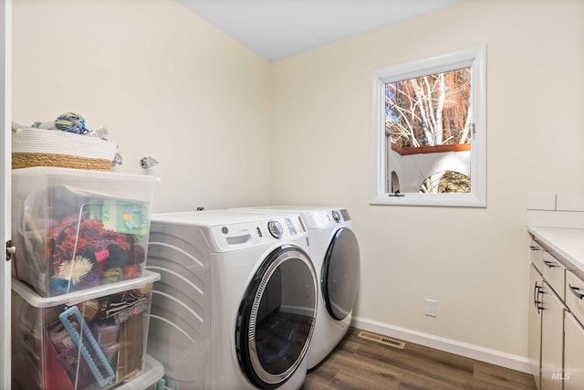 washroom with washer and dryer, dark hardwood / wood-style floors, and cabinets