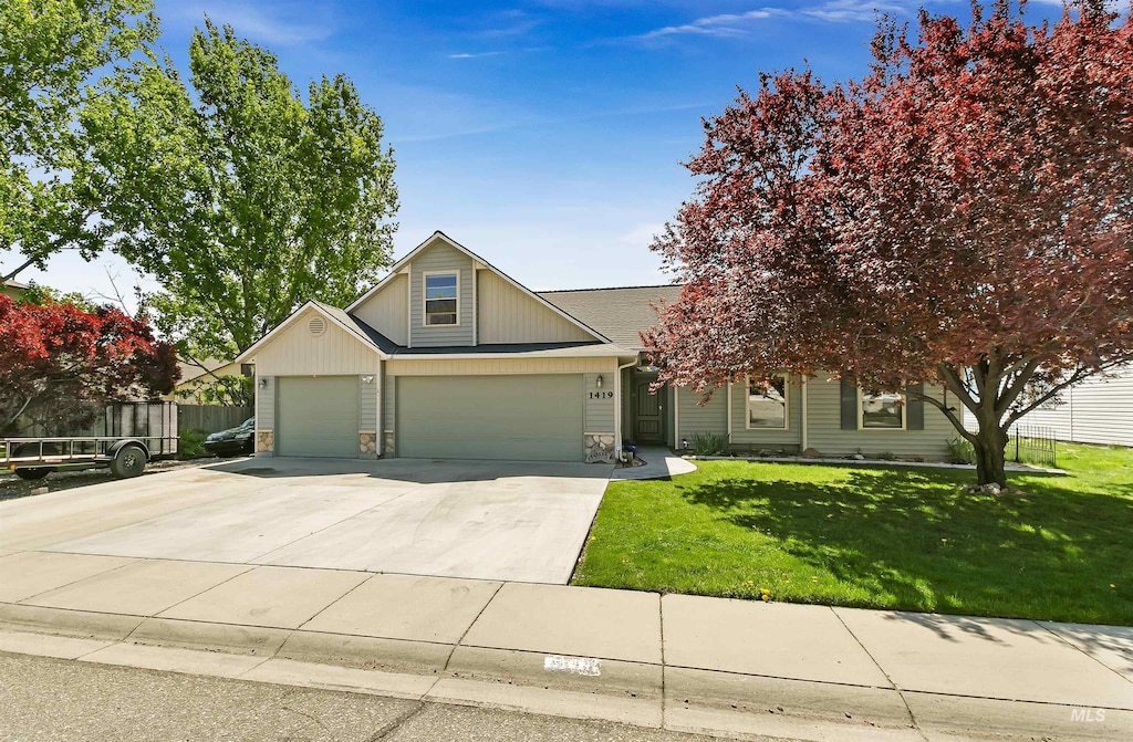 view of front facade featuring a front yard, a garage, fence, concrete driveway, and stone siding