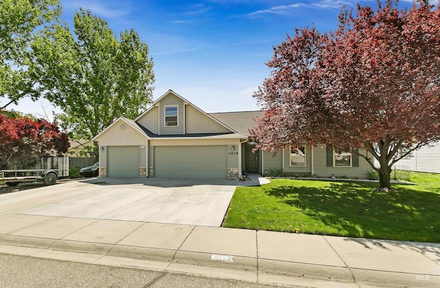 view of front facade featuring a front yard, a garage, fence, concrete driveway, and stone siding