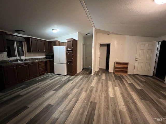 kitchen with a sink, dark brown cabinetry, dark countertops, freestanding refrigerator, and wood finished floors