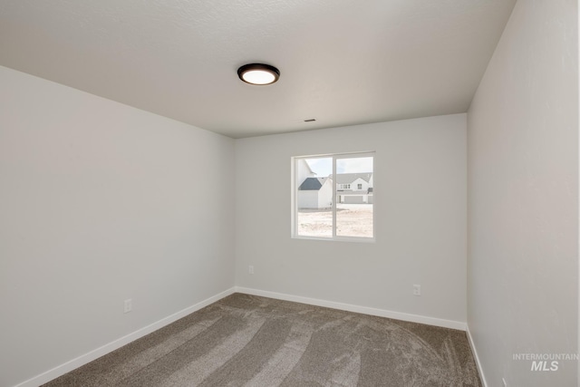 empty room featuring carpet flooring and baseboards