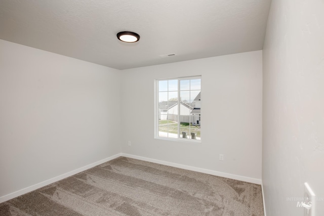 unfurnished room with carpet floors, visible vents, a textured ceiling, and baseboards