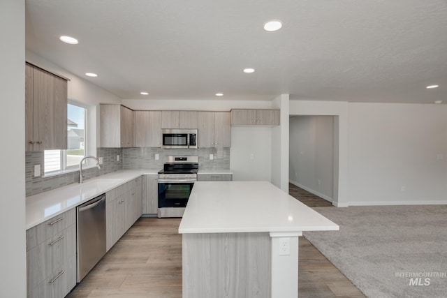 kitchen with stainless steel appliances, a kitchen island, light countertops, tasteful backsplash, and modern cabinets