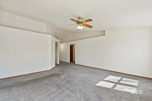 carpeted spare room featuring a textured ceiling, vaulted ceiling, baseboards, and ceiling fan