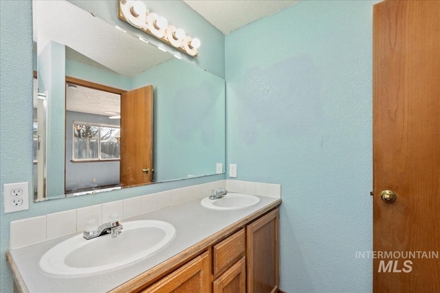 full bathroom with a sink, double vanity, and a textured wall