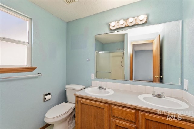 full bath featuring double vanity, a shower stall, toilet, and a sink