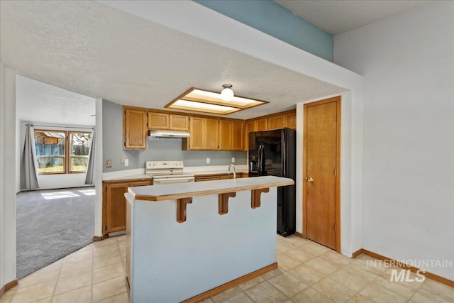 kitchen featuring a center island with sink, black fridge, white electric range, under cabinet range hood, and light countertops