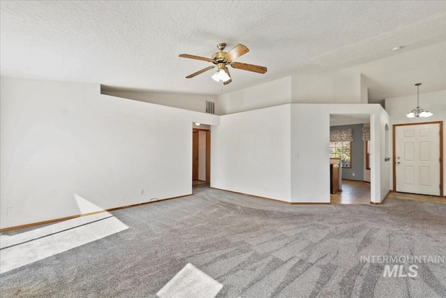 empty room with lofted ceiling, ceiling fan with notable chandelier, visible vents, and carpet floors