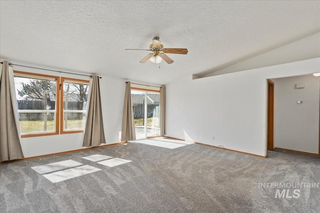 carpeted empty room with vaulted ceiling, a ceiling fan, baseboards, and a textured ceiling