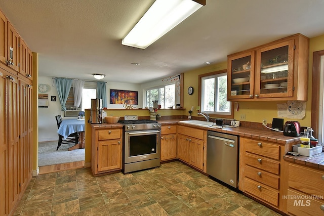 kitchen with stainless steel appliances, tile counters, and sink