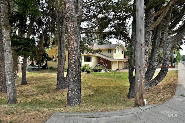 view of property hidden behind natural elements with a garage and a front lawn